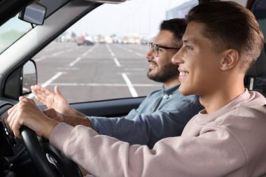 Ehliyet kursu. Otoparkta sürüş eğitmeniyle ders sırasında mutlu öğrenci.