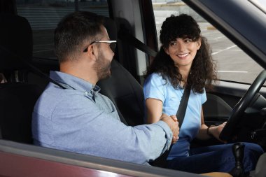 Ehliyet kursu. Otoparkta ders sırasında sürücü eğitmeniyle tokalaşan mutlu öğrenci.