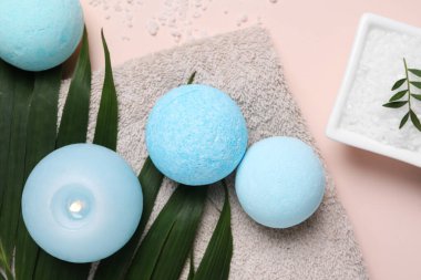 Banyo bombaları, yeşil yaprak, deniz tuzu ve yanan mum bej arka planda, düz uzanmış