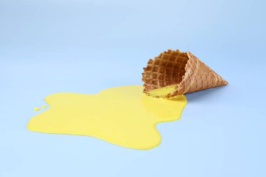 Açık mavi zemin üzerinde erimiş dondurma ve gofret konisi