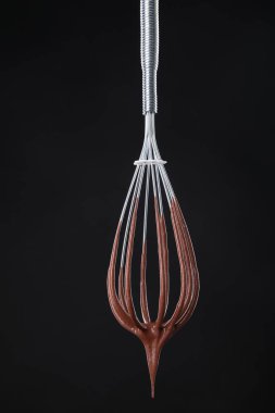 Çikolata kremi siyah arka planda çırpılarak akıyor.