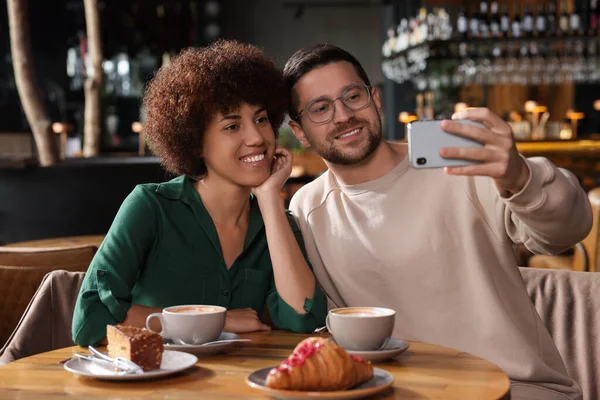 International dating. Happy couple taking selfie in cafe