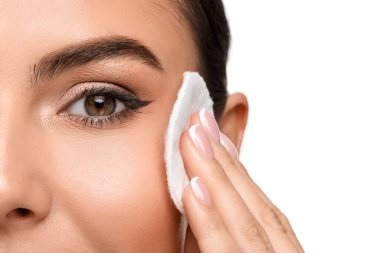 Beyaz arka planda pamuklu ped ile makyajı kaldıran güzel bir kadın.