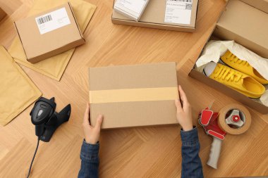 Ahşap masada paketli bir kadın var. Çevrimiçi mağaza