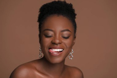 Açık kahverengi arka planda güzel, mutlu bir kadının moda portresi.