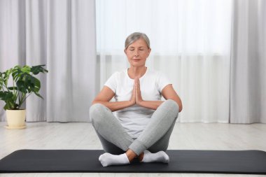 Son sınıf öğrencisi kadın evde yoga yapıyor.