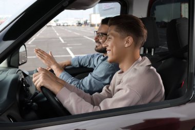 Ehliyet kursu. Otoparkta sürüş eğitmeniyle ders sırasında mutlu öğrenci.