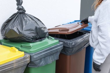 Çöp torbası dolusu çöpü dışarı atmak için çöpü açan kadın, yakın çekim. Geri dönüşüm kavramı