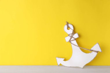 Sarı duvarın yanındaki beyaz ahşap masada kenevir ipli çapa, metin için boşluk.