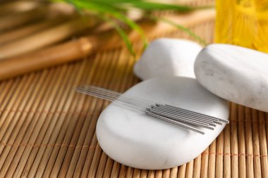 Bambu hasırının üzerinde akupunktur iğneleri ve spa taşları, yakın çekim. Metin için boşluk