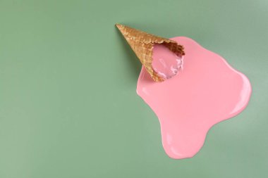 Yeşil arka planda erimiş dondurma ve gofret külahı. Metin için boşluk