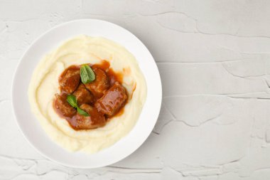 Beyaz desenli masa üzerinde patates püresi ile nefis gulaş, üst manzara. Metin için boşluk