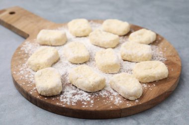 Tembel börekler yapıyorum. Kesik hamurlu tahta ve un gri masada.