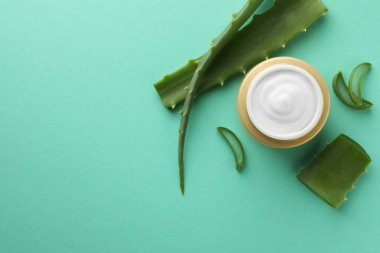 Yeşil arka planda bir kavanoz doğal krema ve aloe yaprağı. Metin için boşluk
