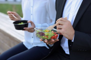 Dışarıdaki beslenme çantalarından yemek yiyen iş adamları, yakın çekim.
