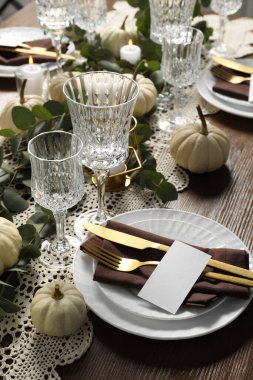 Güzel bir sonbahar sofrası. Tabaklar, çatal bıçak takımı, bardaklar, boş kartlar ve çiçek dekoru.