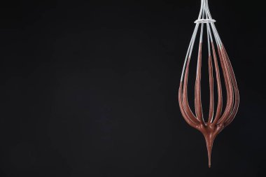 Çikolata kremi siyah arka planda çırpılarak akıyor, yakın plan. Metin için boşluk