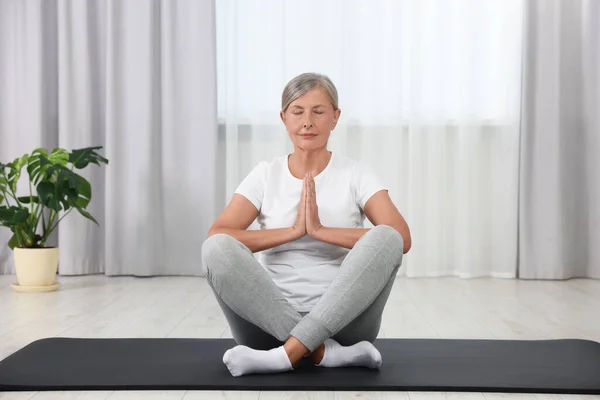 stock image Senior woman practicing yoga on mat at home