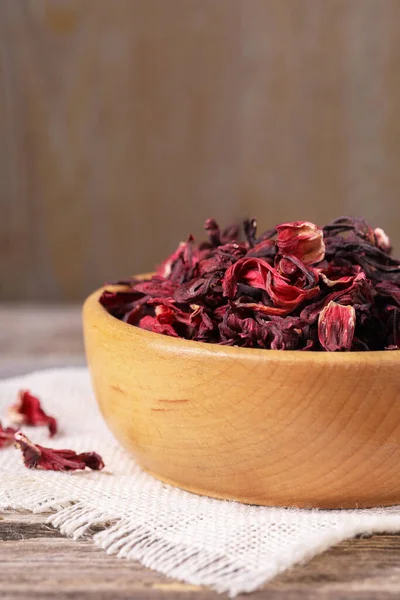 Dry hibiscus tea in bowl on table, closeup