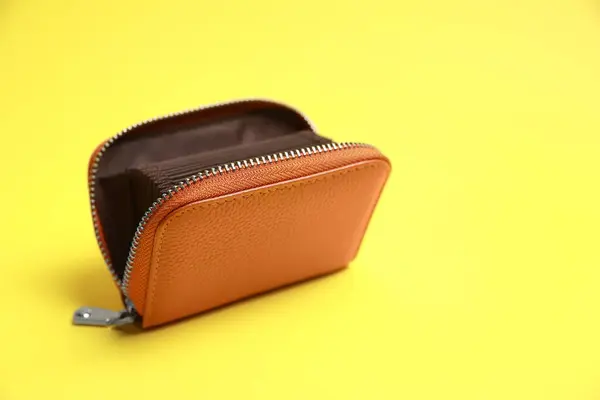 Stylish brown leather purse on yellow background. Space for text