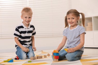 Little children playing with building blocks indoors. Wooden toys clipart