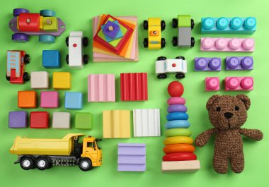 Different children's toys on green background, flat lay clipart