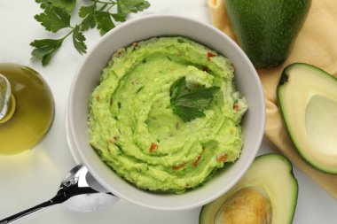 Lezzetli guacamole ve malzemeler beyaz masada, düz yerde.