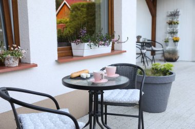 Bardaklar dolusu kahve, ekmek ve peynir cam masada. Açık terasta dinlenme yeri