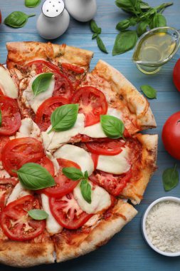 Lezzetli Caprese pizzası ve malzemeler mavi ahşap masada, düz yatıyordu.