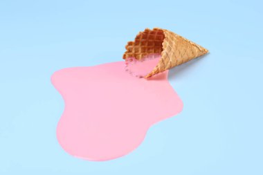Açık mavi zemin üzerinde erimiş dondurma ve gofret konisi