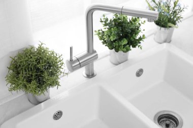 Mutfaktaki tezgahın üstünde farklı saksıda suni bitkiler var. Ev dekoru