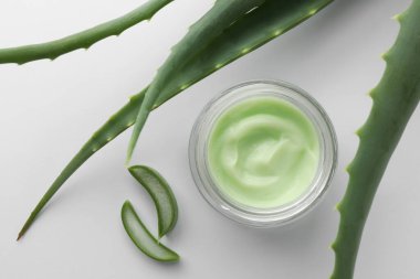 Beyaz arka planda doğal krema ve aloe yaprakları var.