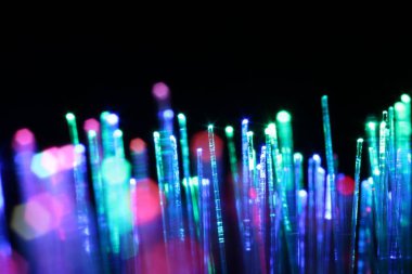 Optik fiber iplikler siyah arkaplan üzerinde farklı renk ışıkları iletiyor, makro görünüm