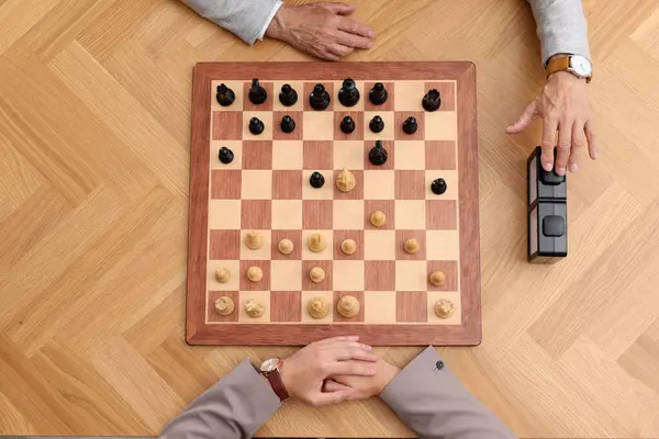 Player turning on chess clock during tournament at wooden table, top view