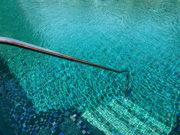 Metal rail and steps in outdoor swimming pool