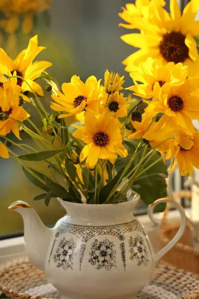 Beautiful flowers in teapot on table, closeup. Autumn atmosphere