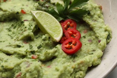 Limon, biber ve maydanozla servis edilen bir kase lezzetli guacamole.