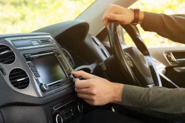 Araba sürerken radyo dinlemek. Aracın ses düğmesini çeviren adam, kapat
