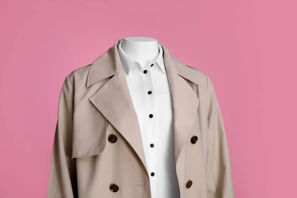 Female mannequin dressed in stylish stretch coat and shirt on pink background