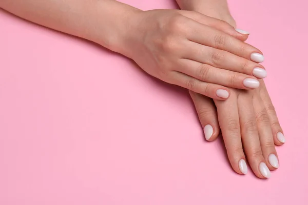 Woman showing her manicured hands with white nail polish on pink background, closeup. Space for text