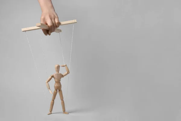 stock image Woman pulling strings of puppet on light grey background, closeup. Space for text