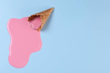 Açık mavi arka planda erimiş dondurma ve gofret külahı. Metin için boşluk