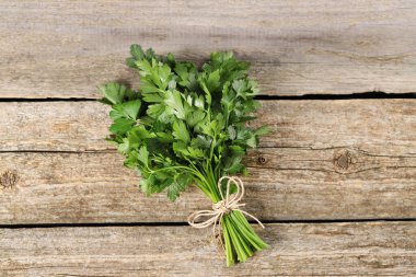 Tahta masanın üstünde yeşil maydanoz yaprakları var.