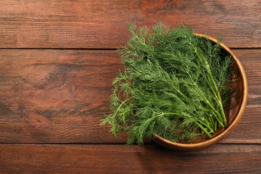 Bir kase taze dereotu ahşap masada, üst manzara. Metin için boşluk