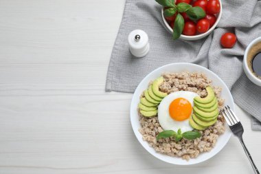 Lezzetli haşlanmış yulaf ezmesi, sahanda yumurta ve beyaz ahşap masada servis edilen avokado. Metin için boşluk