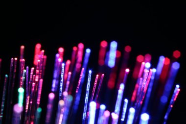 Optik fiber iplikler siyah arkaplan üzerinde farklı renk ışıkları iletiyor, makro görünüm