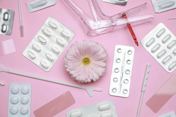 Many gynecological tools, pills and gerbera flower on pink background, flat lay