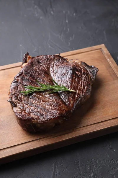 Lezzetli kızarmış biftekli ahşap tahta tahta ve gri desenli masada biberiye.