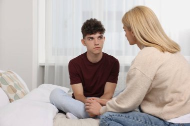 Mother consoling her upset son in bedroom, space for text. Teenager problems clipart