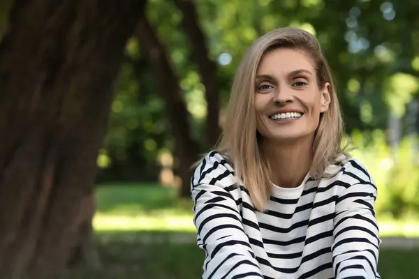 Portrait of happy woman in casual clothes outdoors. Space for text. Attractive lady smiling and posing for camera